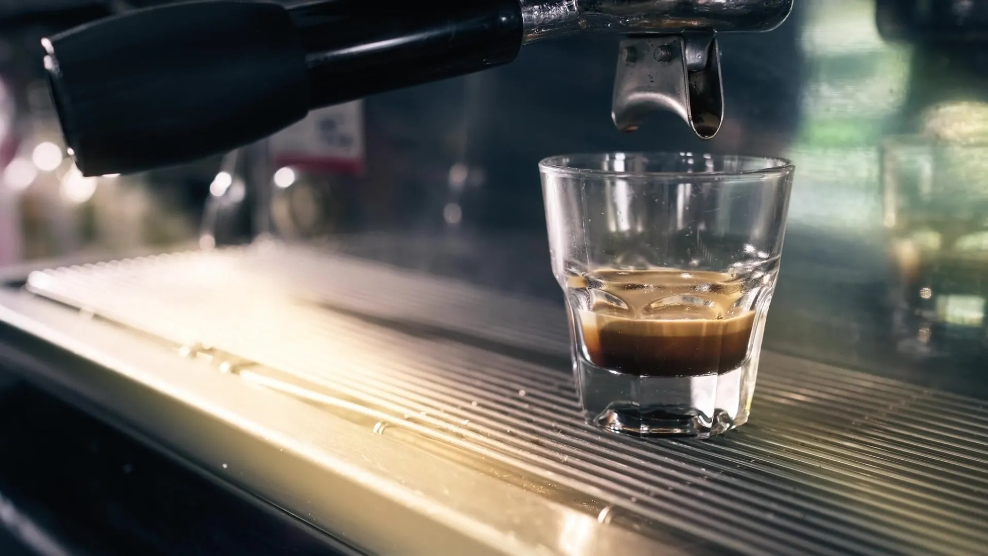 Espresso care curge din portafiltru într-un pahar mic de sticlă